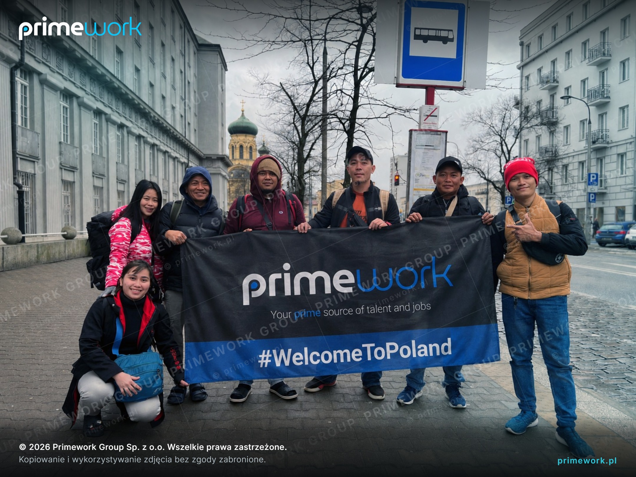 A group of Filipino workers with a Primework #WelcomeToPoland banner after arriving in Warsaw