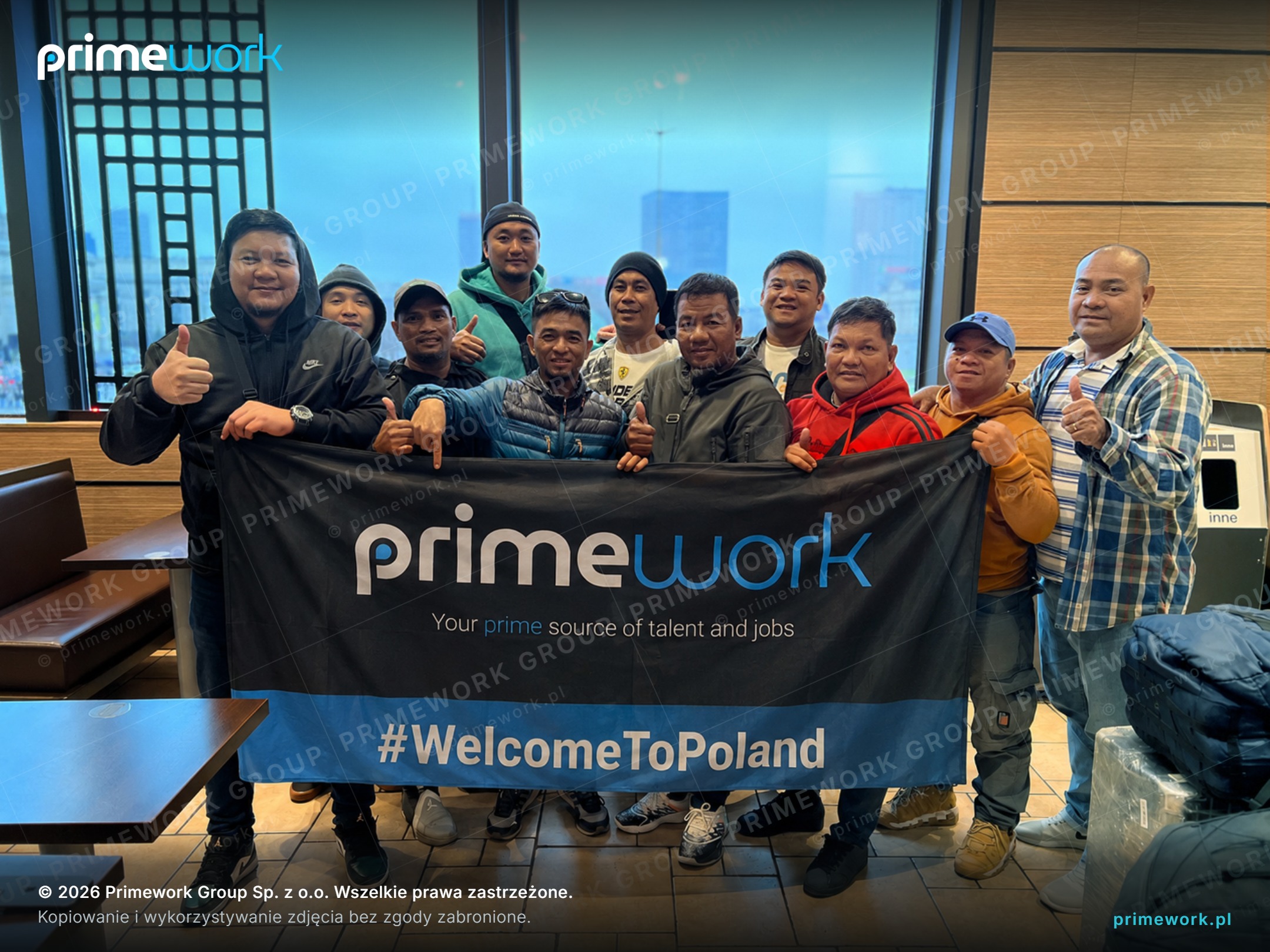 Filipino workers with a Primework banner in a station hall after arriving in Poland