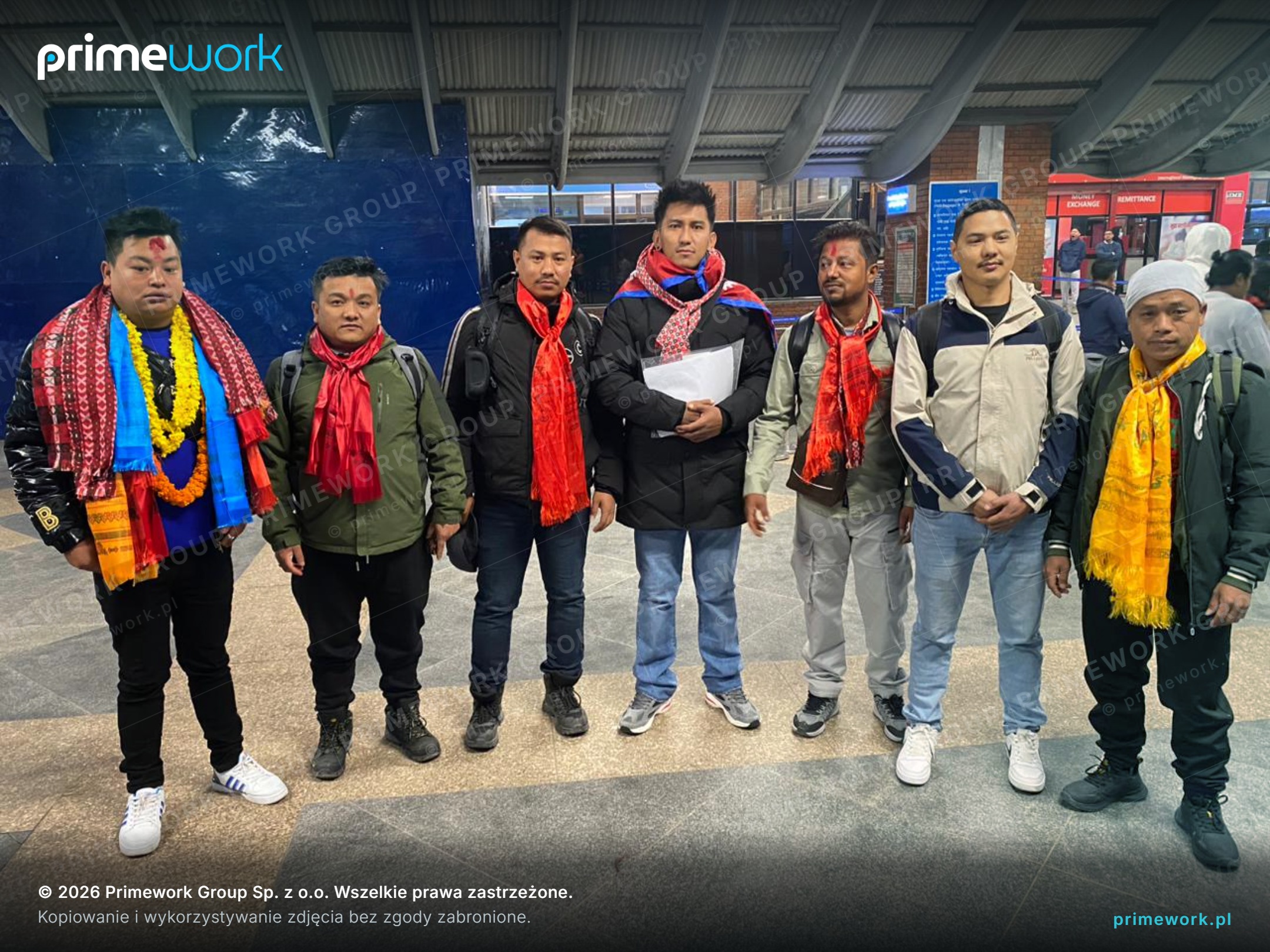Grupa pracowników z Nepalu z tradycyjnymi szalami przed nocnym wylotem do Polski