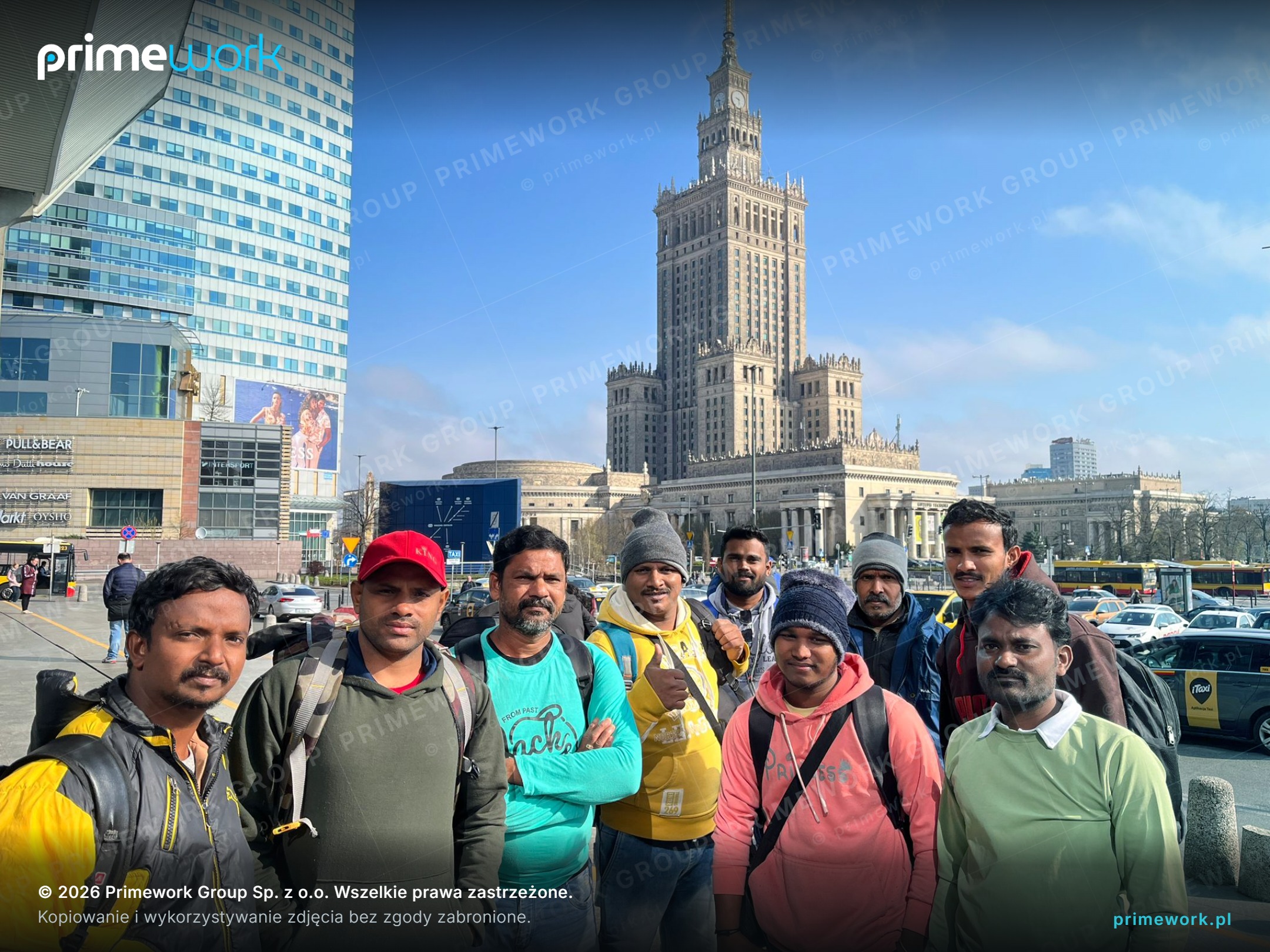 A team of workers from India with backpacks in front of the Palace of Culture and Science in Warsaw