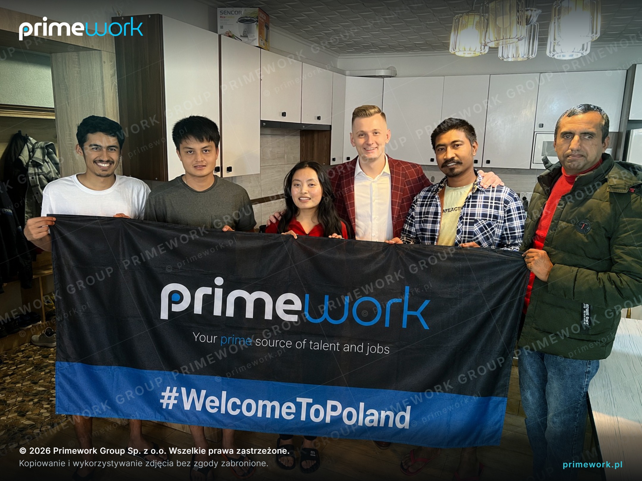 Foreign workers with a Primework banner in the equipped kitchen of a worker flat